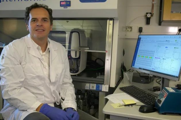 Filipe Pereira sitting in a lab with a labcoat. Photo